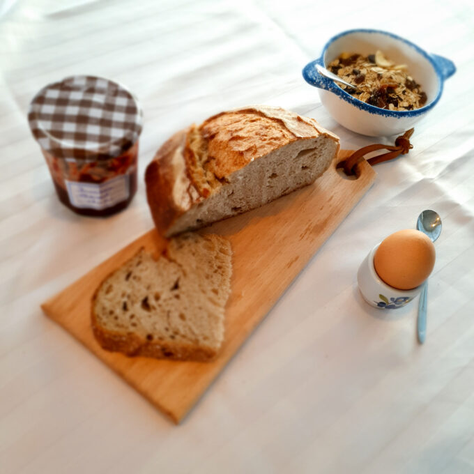 Planche à découper en bois poru lel petit déjeuner avec du pain, un oeuf à la coque, de la confiture et des céréales