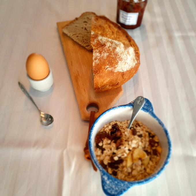 Planche à découper en bois poru lel petit déjeuner avec du pain, un oeuf à la coque, de la confiture et des céréales